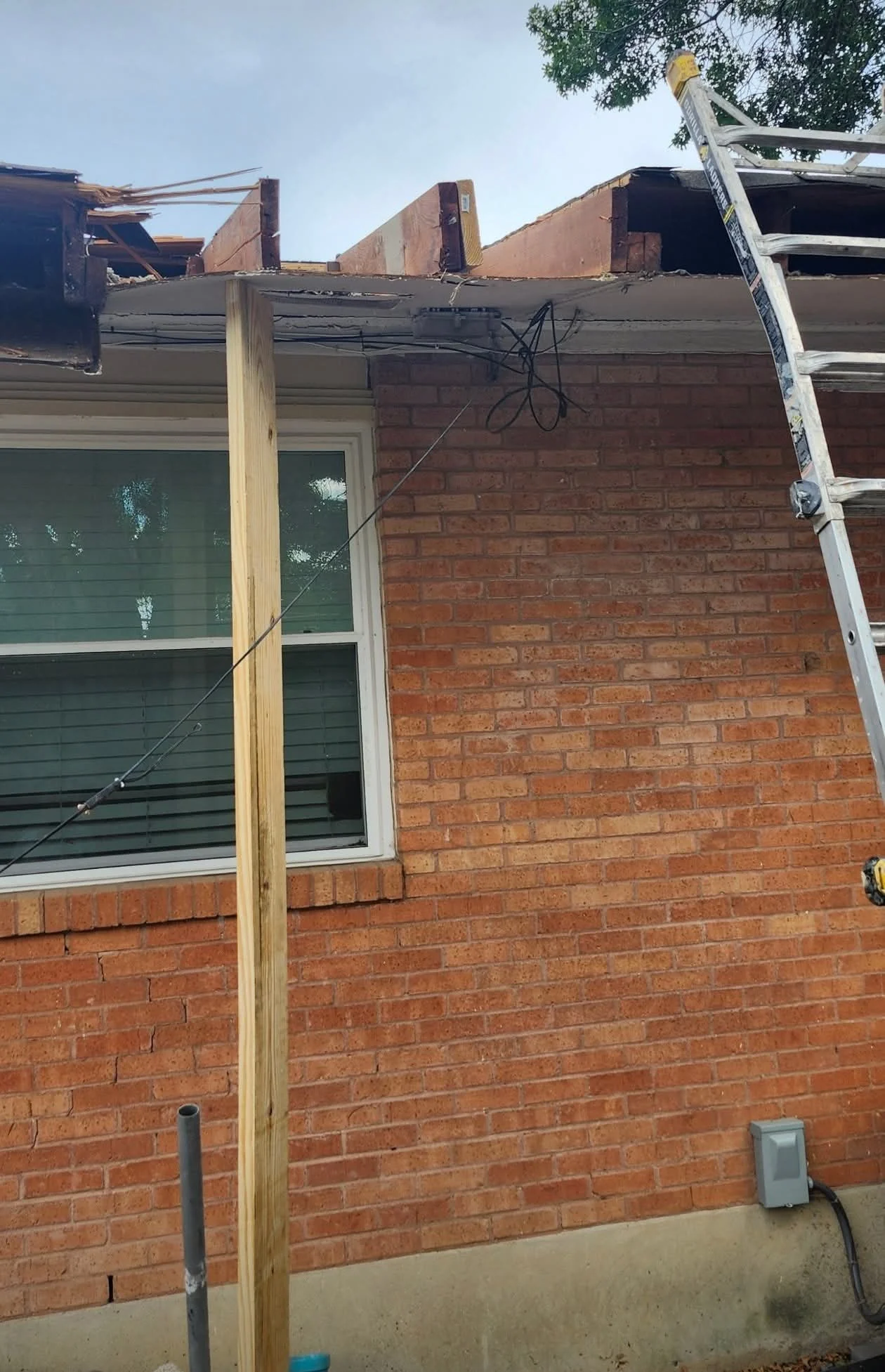 Exposed rafter ends and temporary support at the opened roofline
