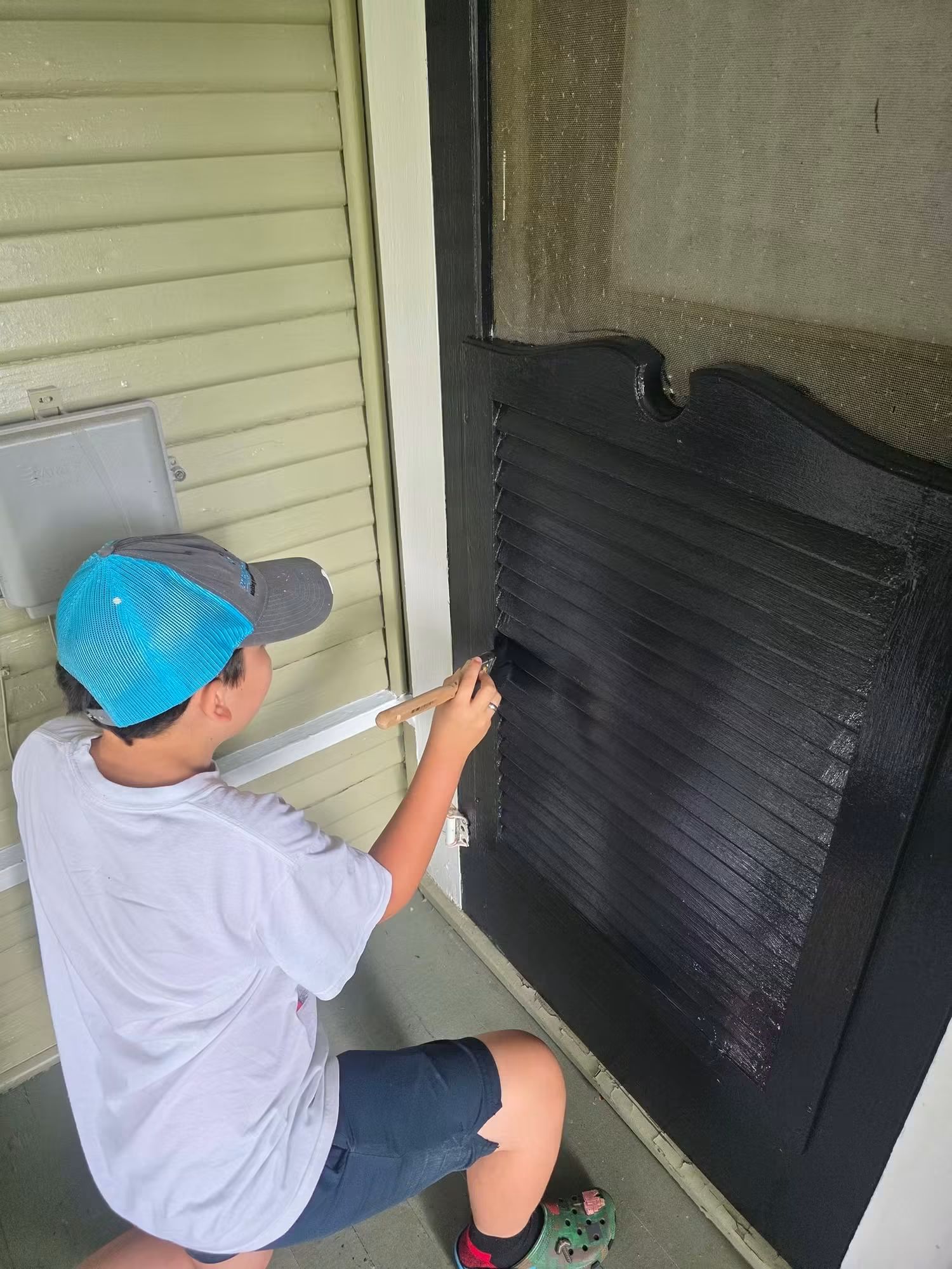 Alexander brushing the dark exterior door during the Terrell restoration