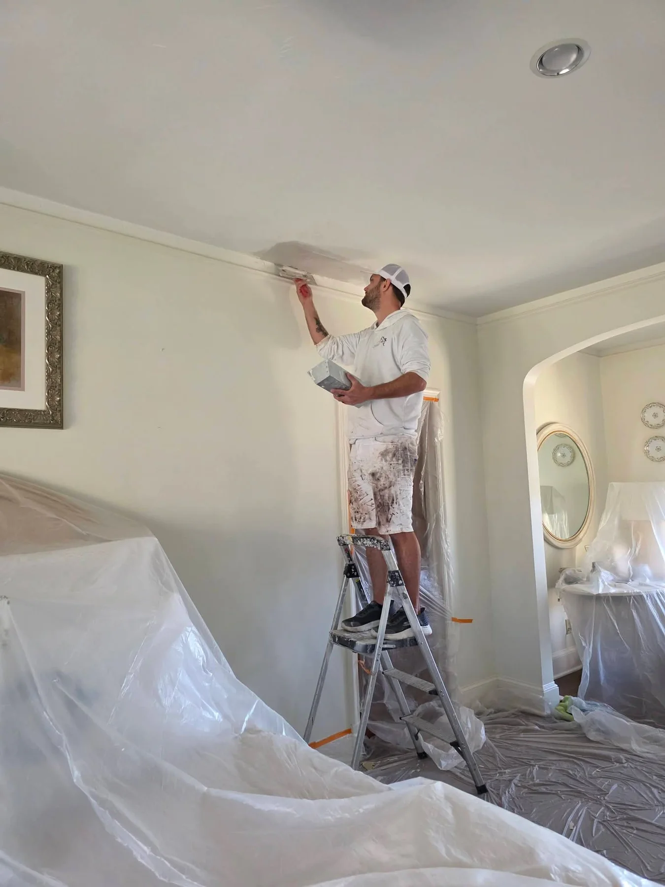 Daltonn finishing a ceiling drywall repair with the room protected below