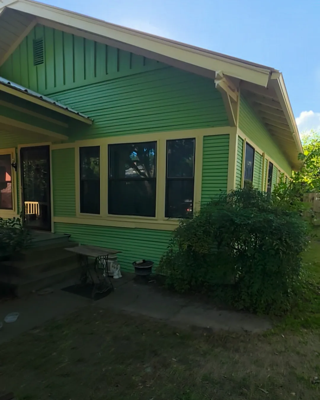 Finished front corner of the green bungalow with cream trim, porch, and windows
