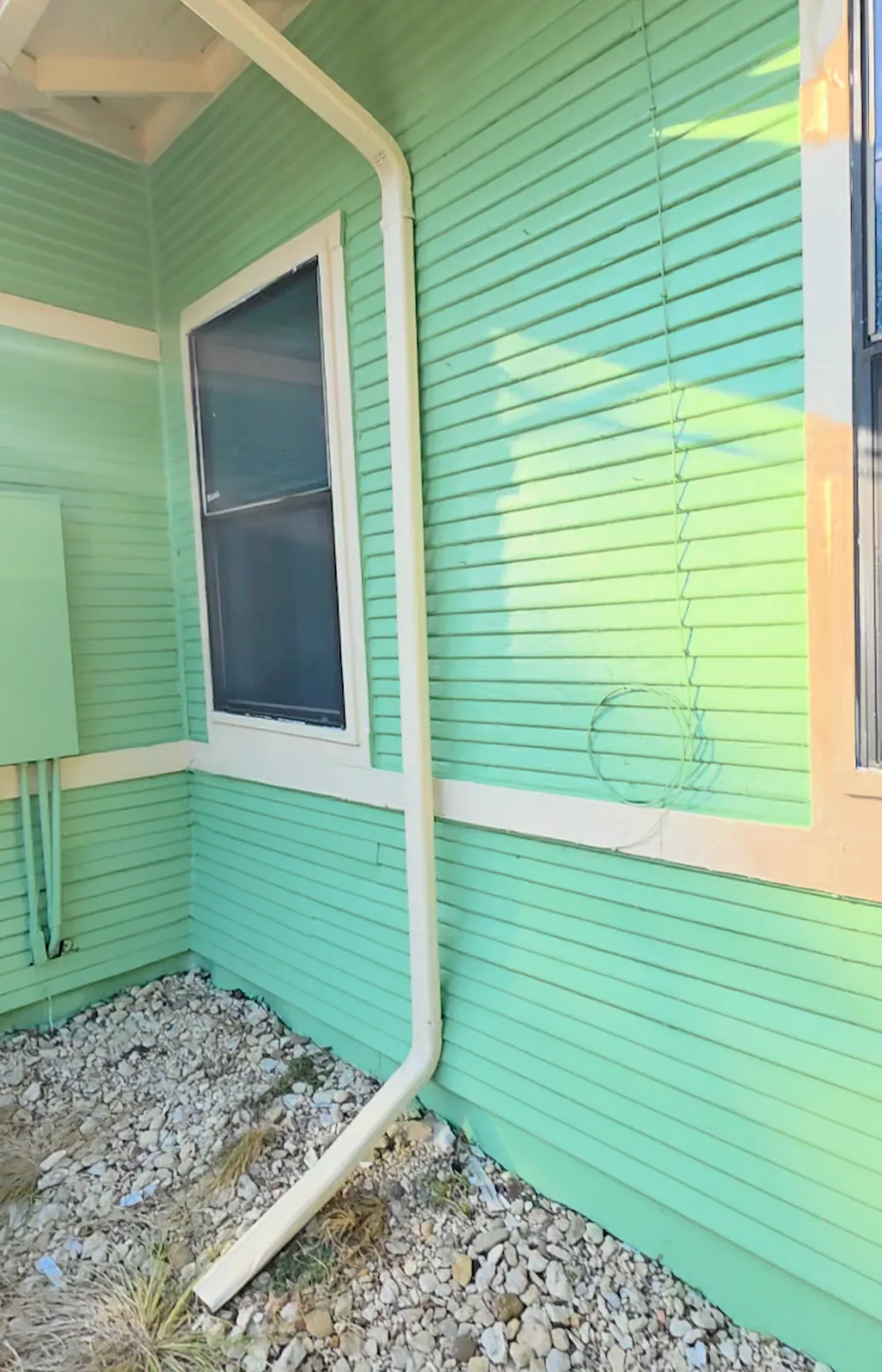 Finished green siding and cream trim at an exterior corner