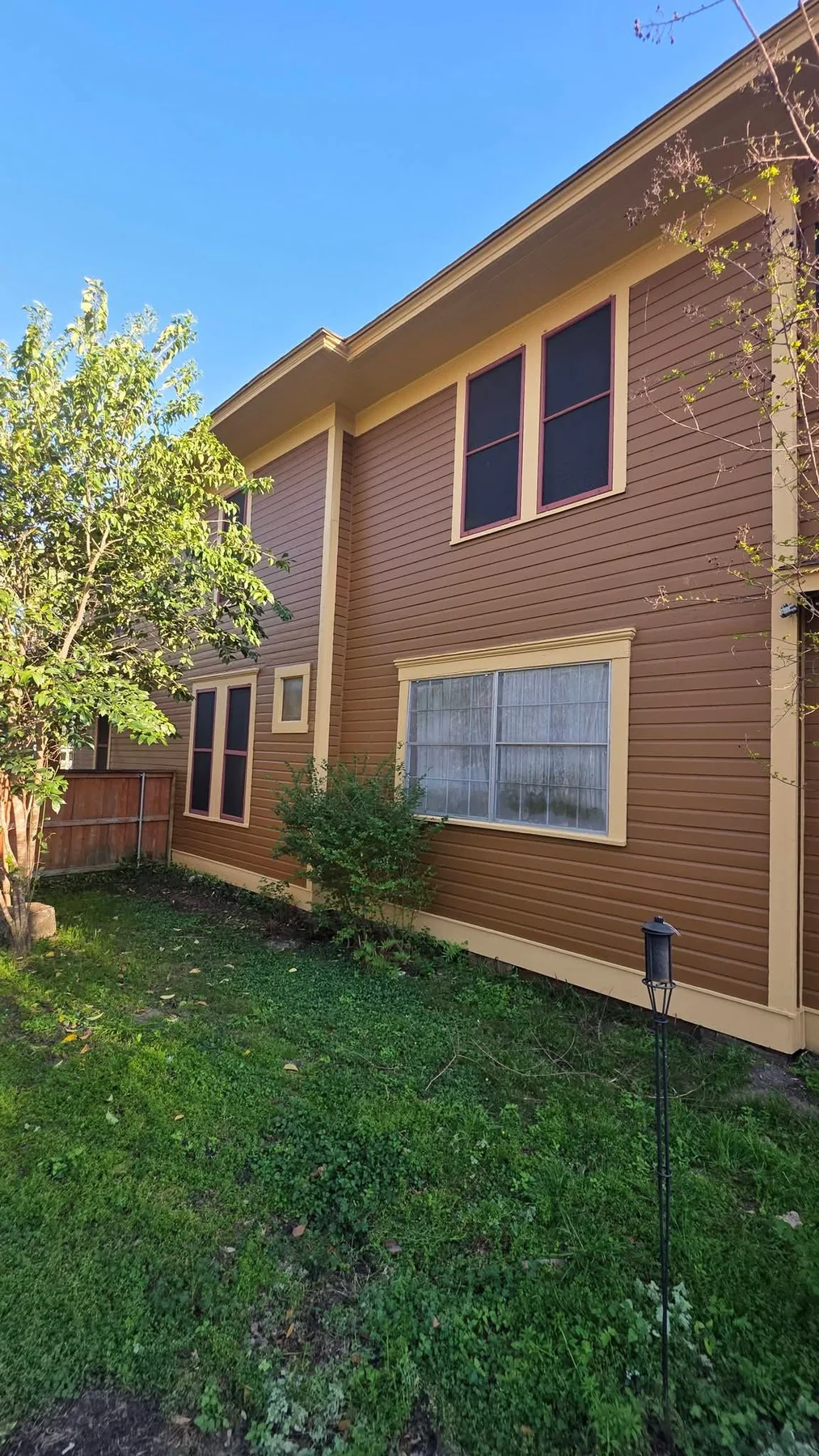 Tall finished side view showing the restored two-story siding and trim