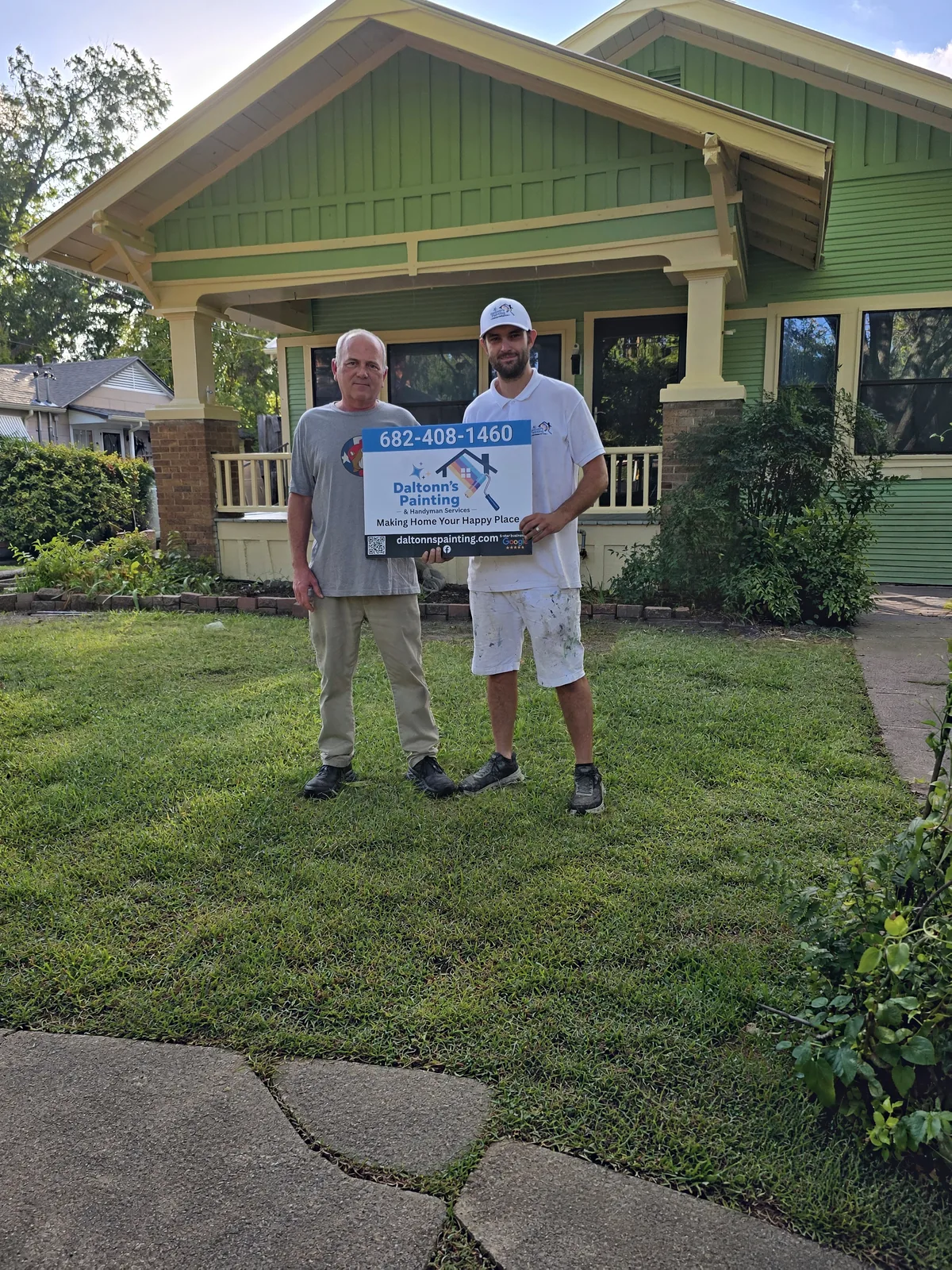 Daltonn and the customer holding a Daltonn’s yard sign in front of the finished bungalow
