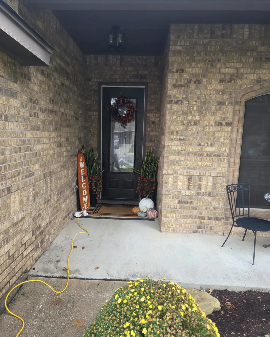 Front door and porch with the original tan and brown brick before limewash
