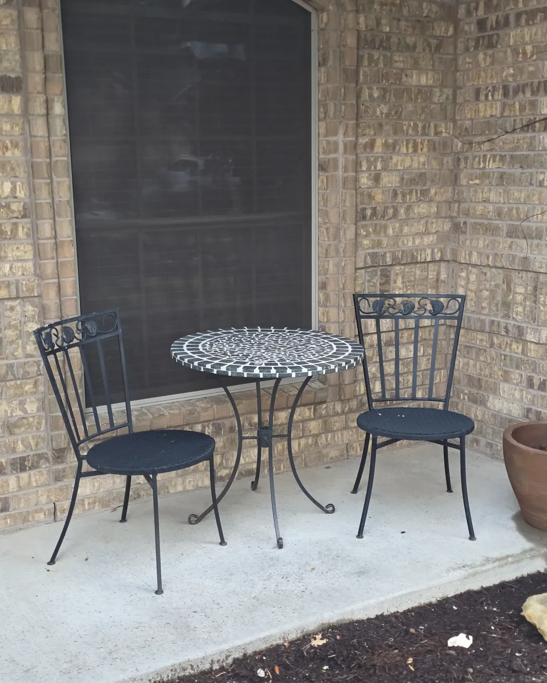 Porch window and bistro table against the original tan brick