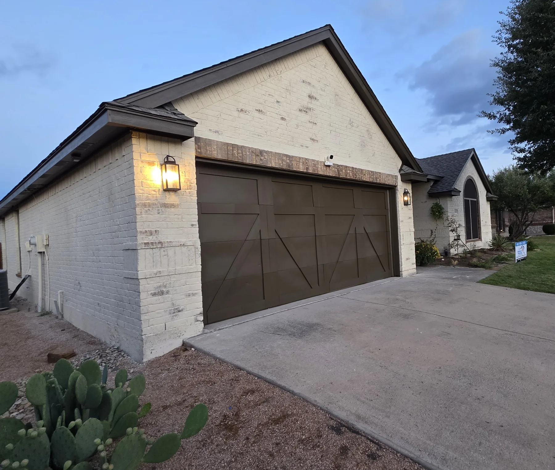 Cream limewashed brick on the garage side of a house finished by Daltonn and his crew, with a dark carriage garage door