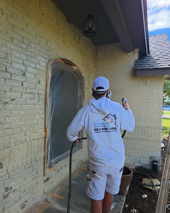 Limewash being washed back with a hose around a covered arched window