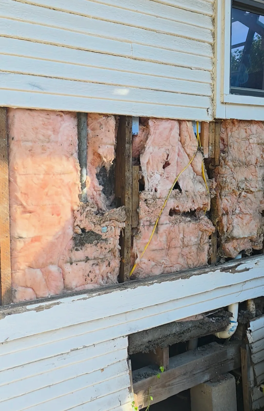 Wall opened below the window with the old patch boards removed and the framing exposed