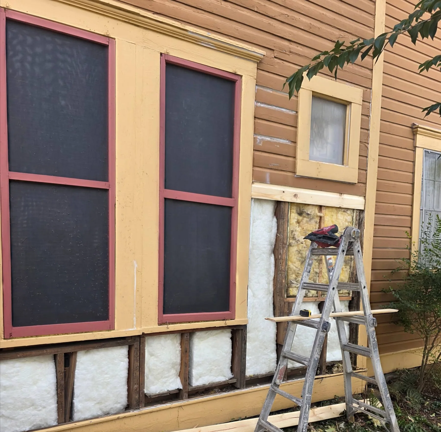 Wide view of the opened exterior wall with framing and insulation visible