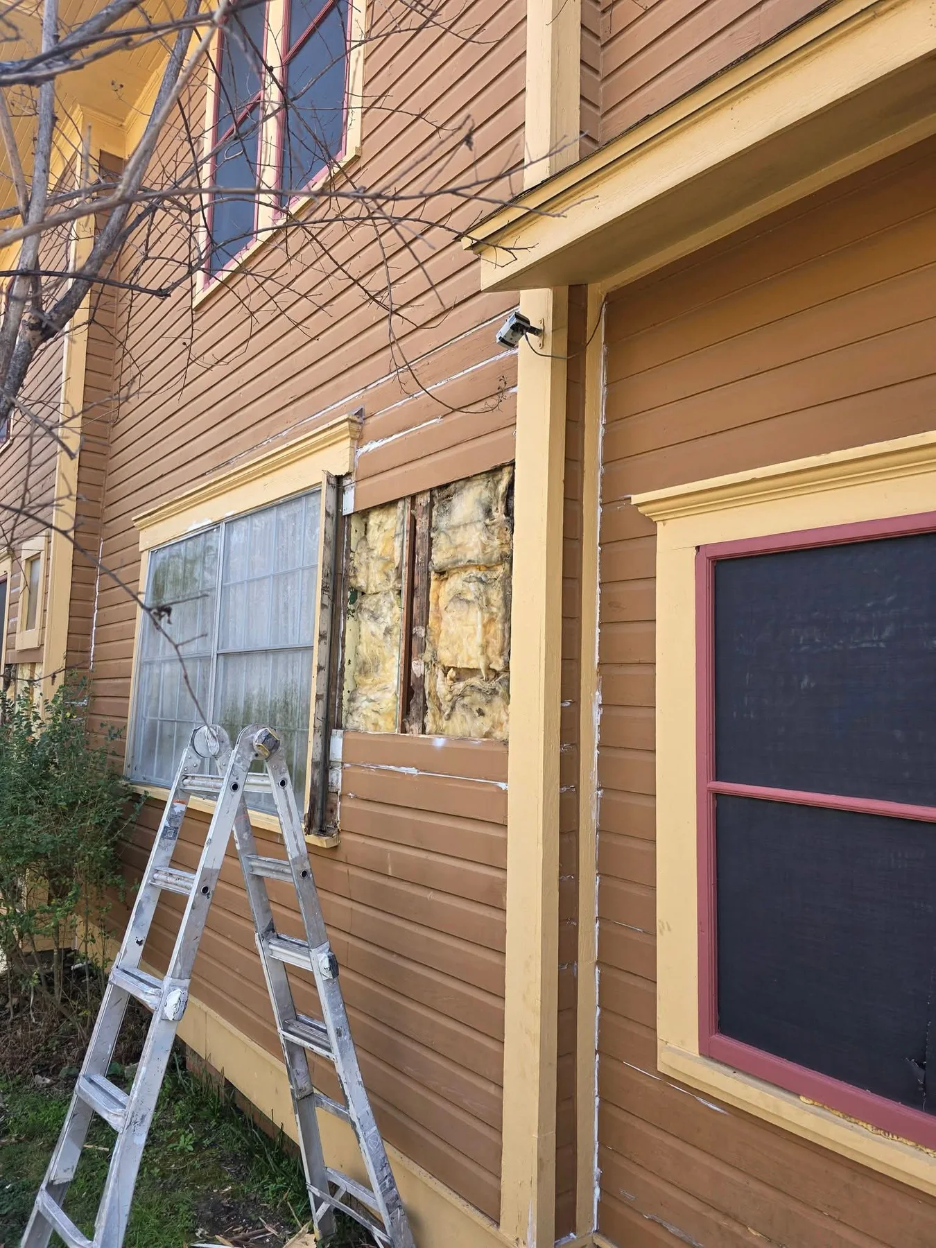 Opened siding and wall area beside an exterior window during repair