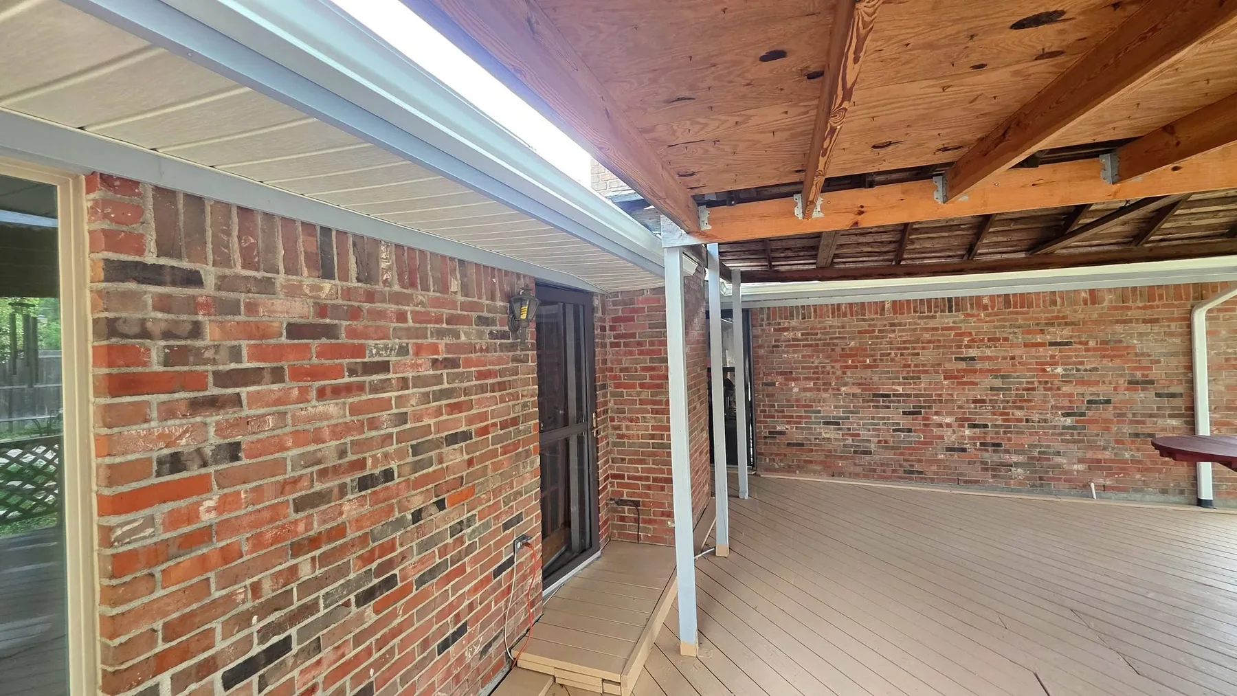 Completed covered deck structure and floor viewed toward the brick wall before furnishing