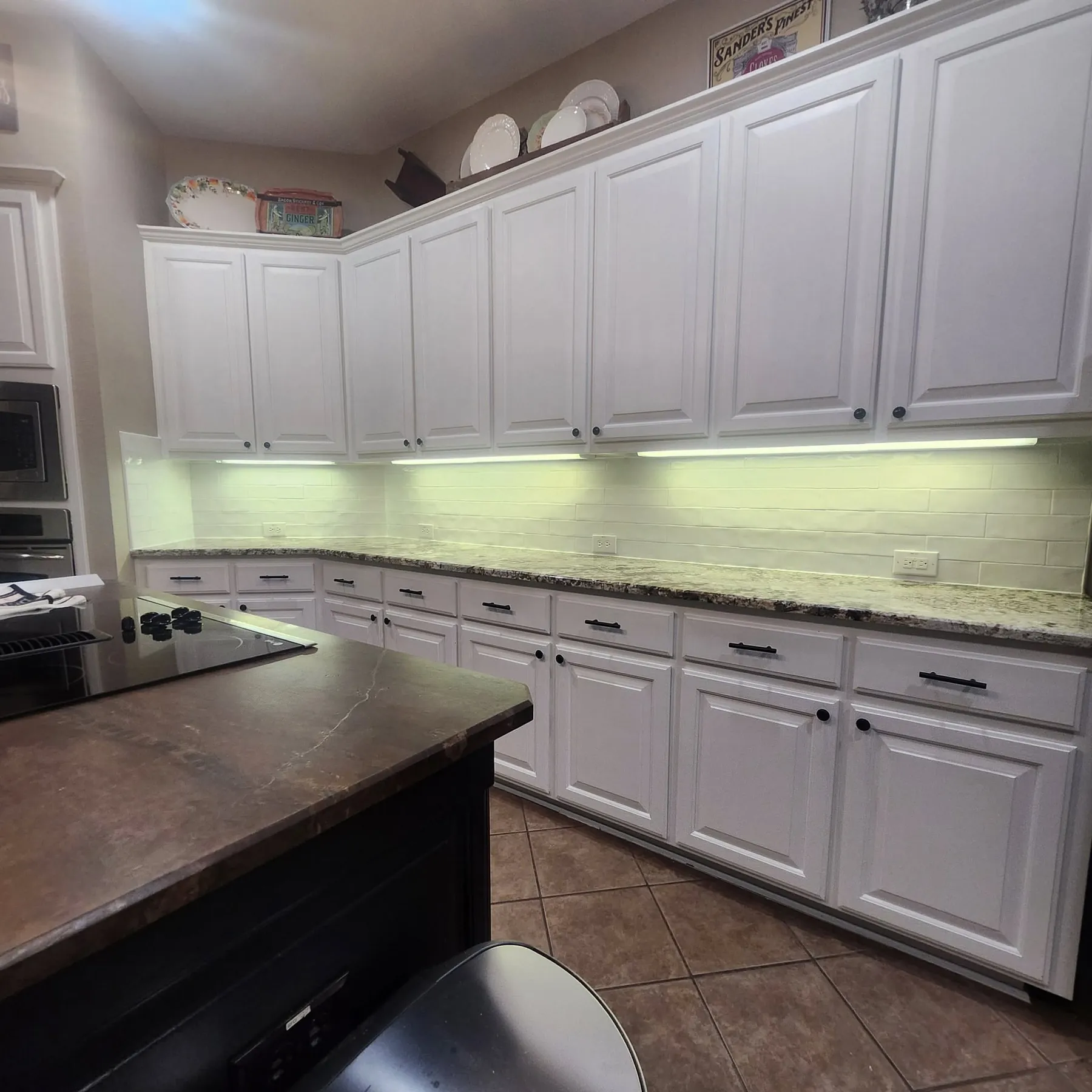 Finished white kitchen with a new white tile backsplash and under-cabinet lighting