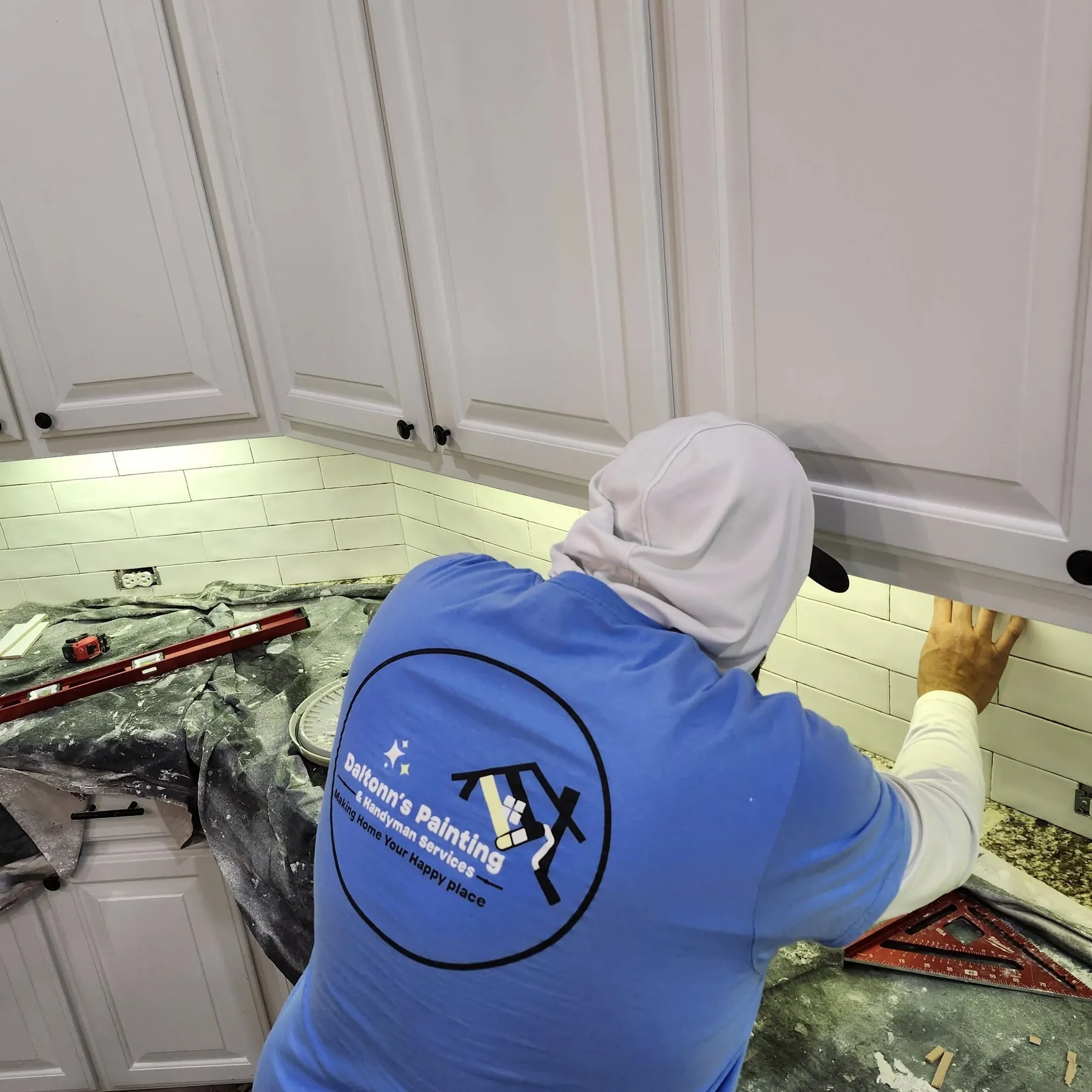Daltonn’s installer setting new white tile beneath the upper cabinets