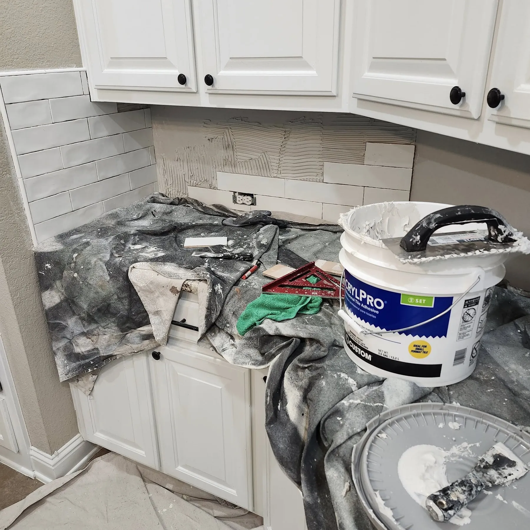 New white tile going onto the prepared wall with the counter protected