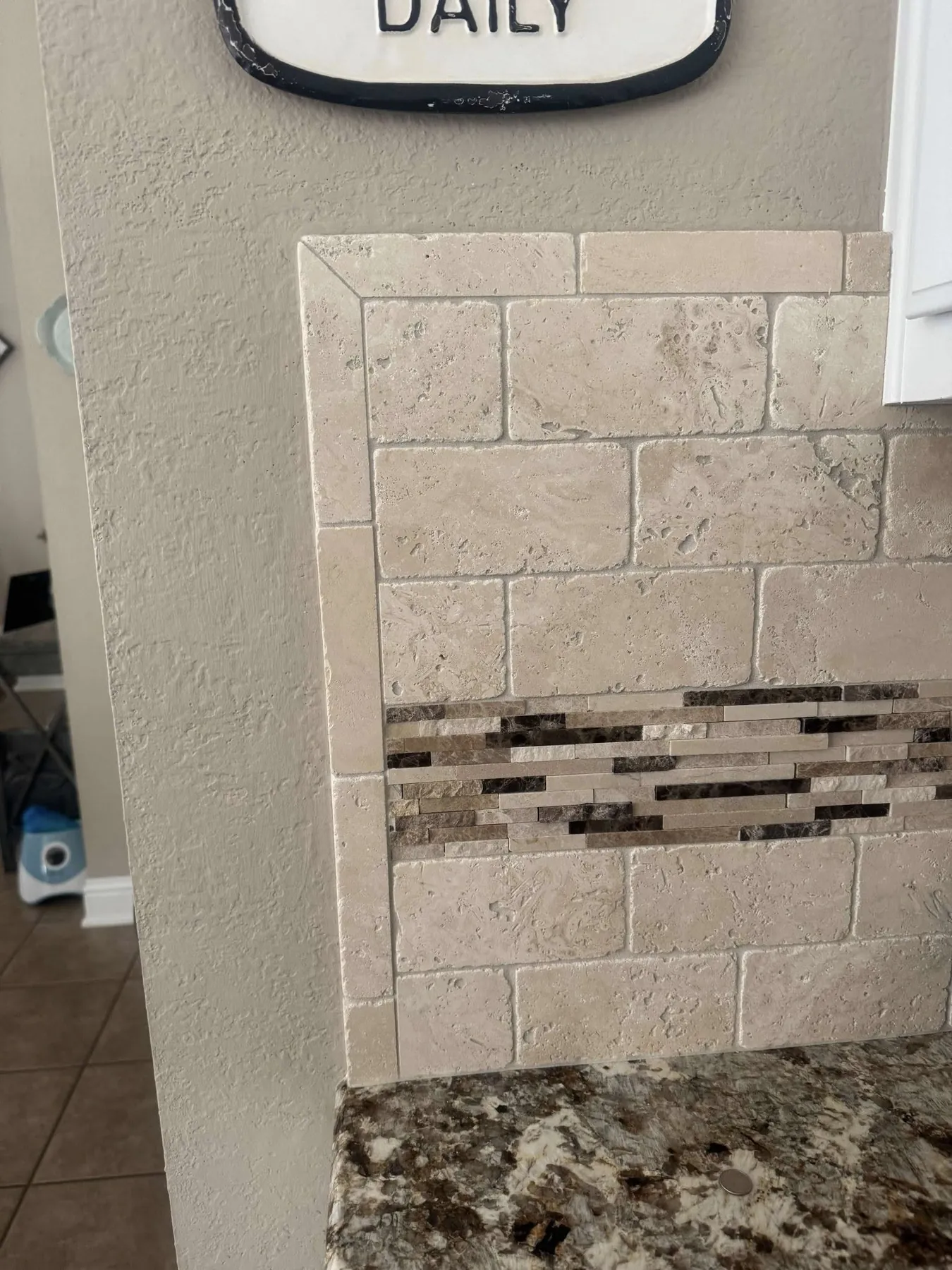 Close view of the original travertine tile and glass-mosaic accent strip