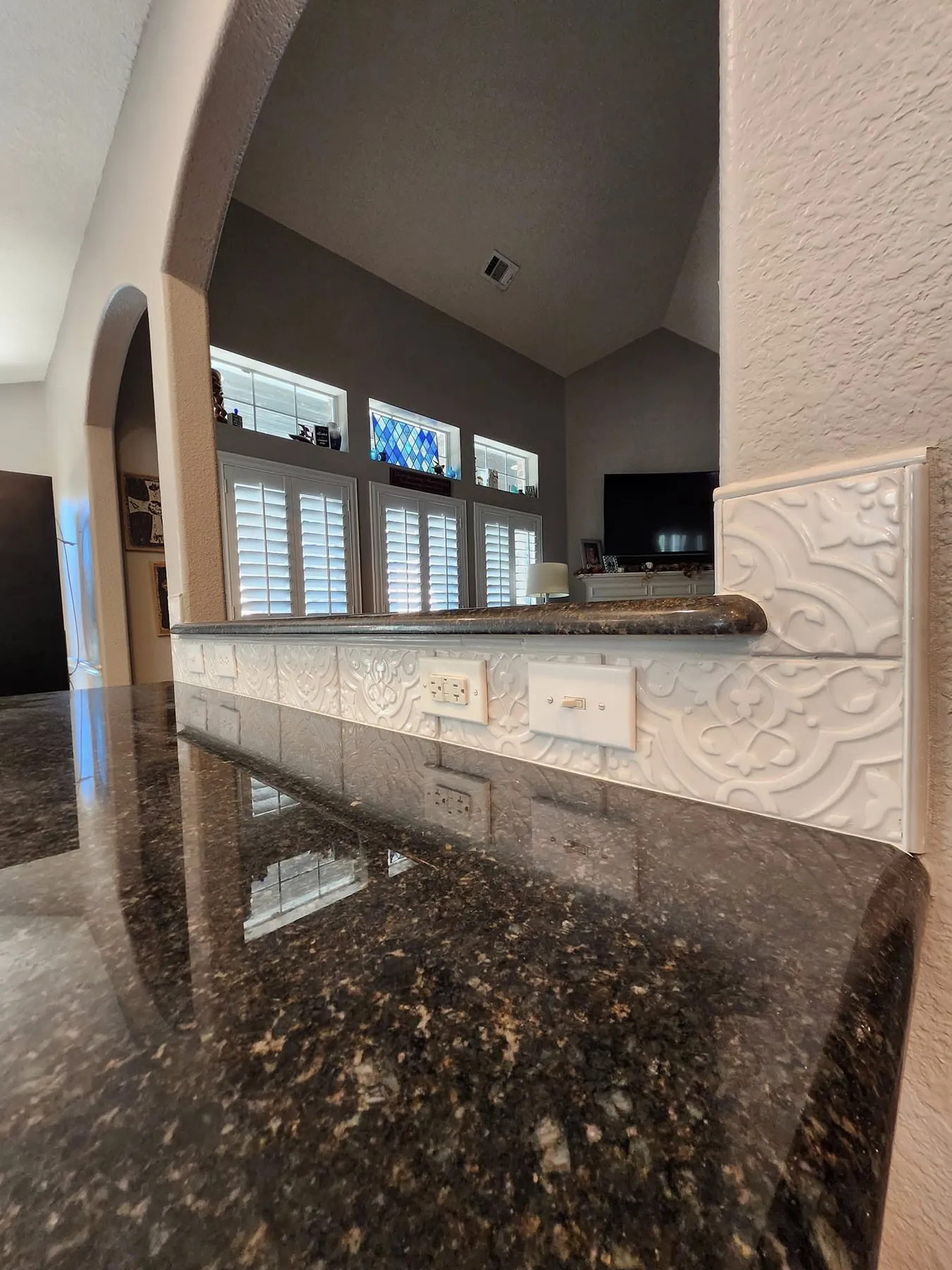 Finished green-gray cabinets beside the dark granite counter