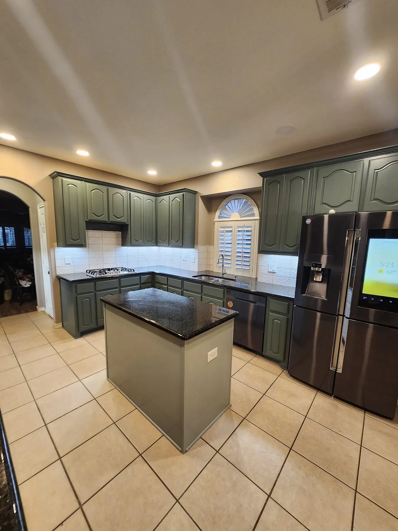 Wide completed kitchen with green-gray painted cabinets and island
