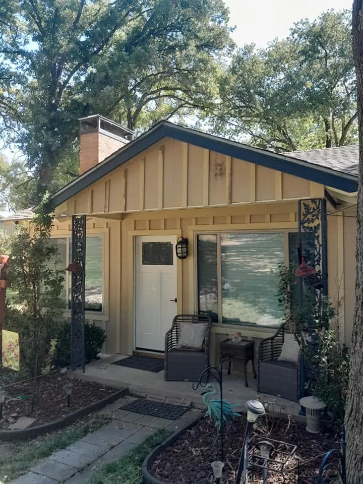 Small cottage front with tan siding and front gable before exterior work