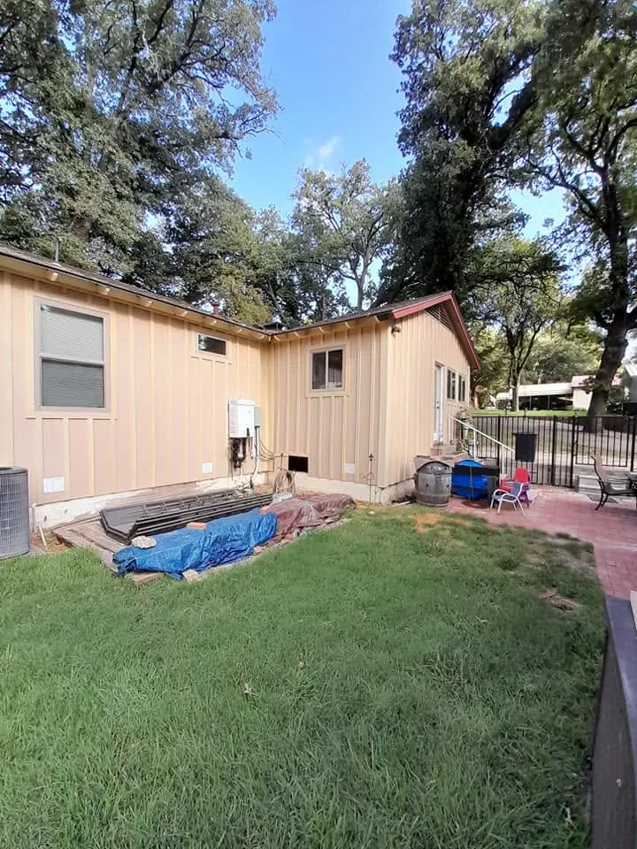 Rear service corner at the tan cottage with protection and materials staged